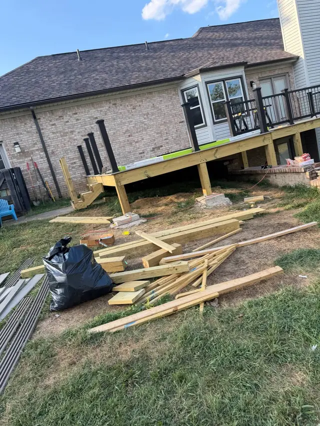 Black post sleeves and partly installed railing panels with construction materials beside the deck Black post sleeves and partly installed railing panels with construction materials beside the deck
