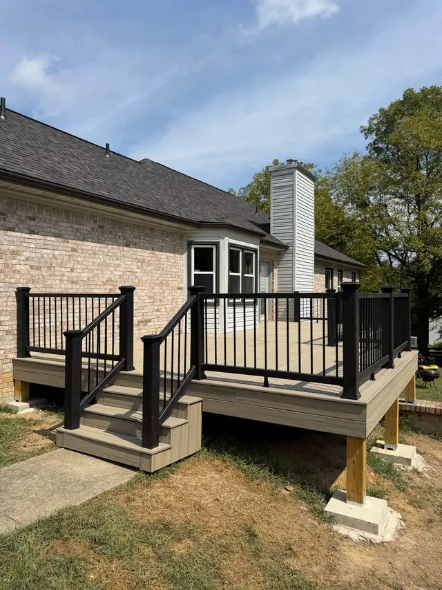 Completed composite deck with front steps and black railings in Crestwood, Kentucky Completed composite deck with front steps and black railings in Crestwood, Kentucky