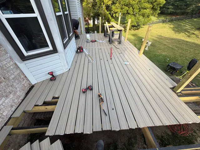 Partly installed composite deck boards with exposed joists, fasteners and tools Partly installed composite deck boards with exposed joists, fasteners and tools