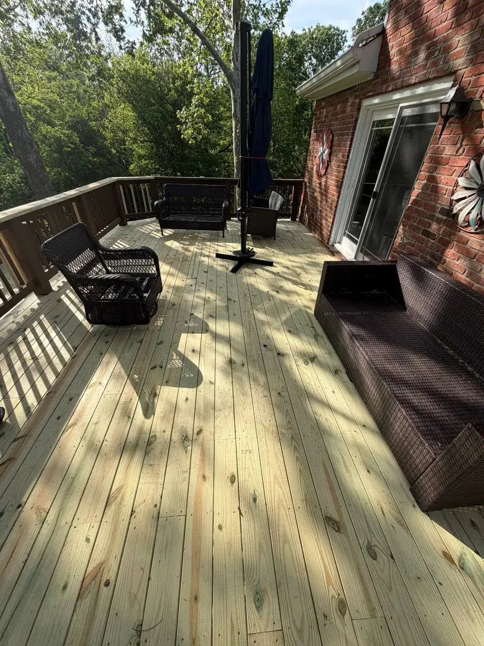 Finished pressure-treated wood deck surface beside a brick home