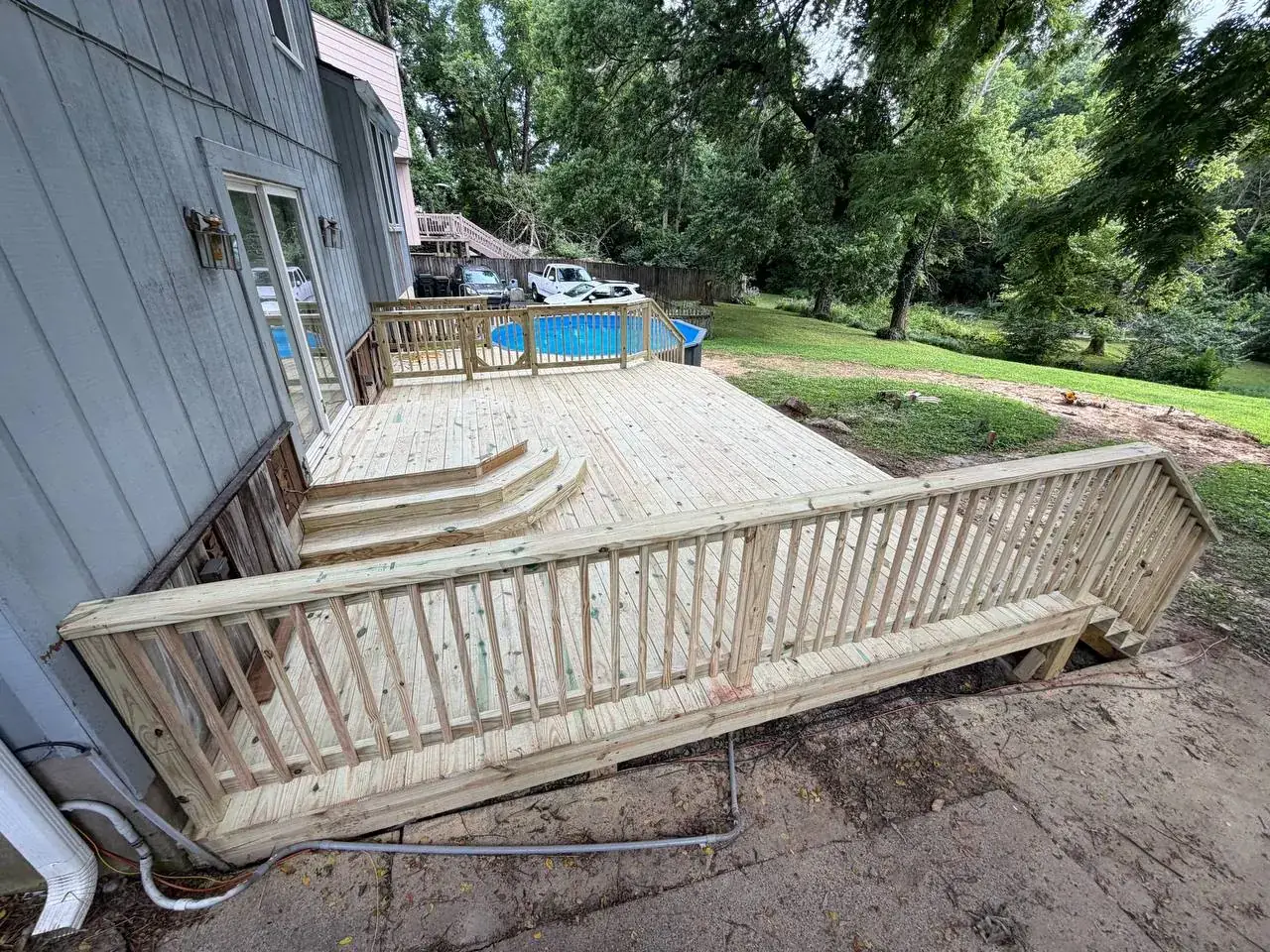 Completed pressure-treated deck beside an above-ground pool