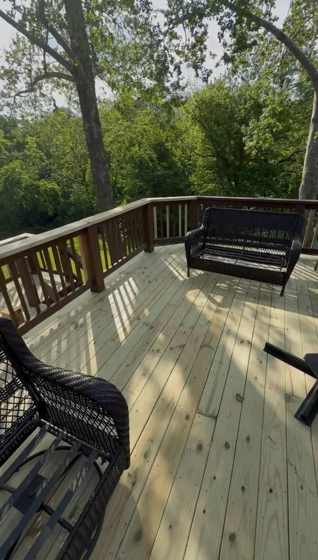 Fresh upper-level wood decking and completed railings beside dark wicker seating