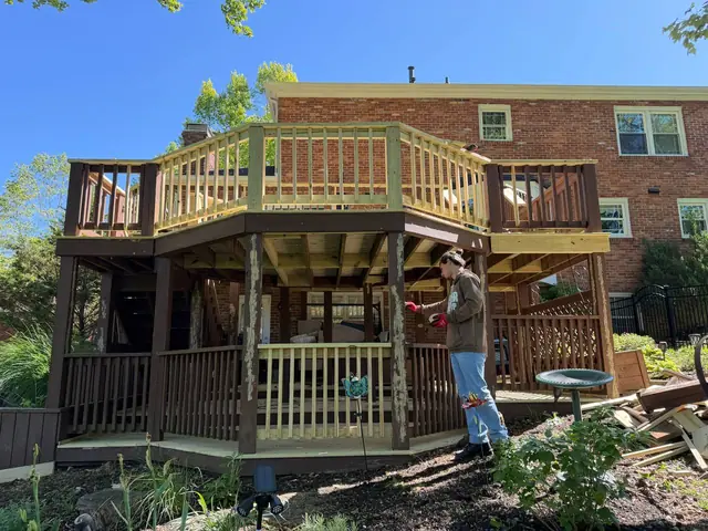 Crew member applying cosmetic wood filler to an existing support post beneath the restored deck