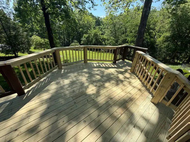 Finished middle deck with new pressure treated boards, balusters and top rails overlooking a wooded backyard