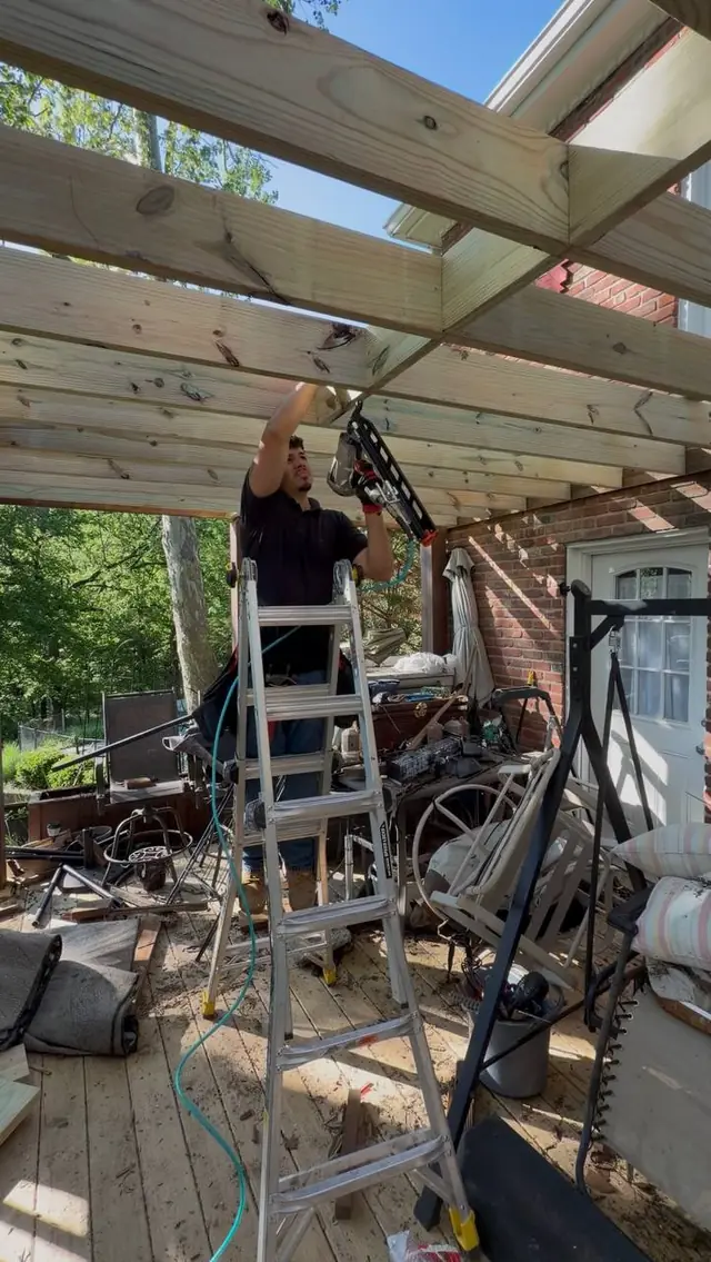 Crew member on a ladder fastening blocking between new pressure treated joists under the upper deck