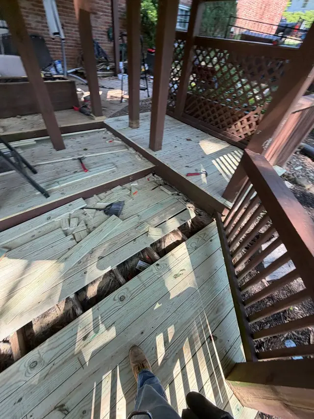 Partly installed pressure treated boards on the lower level with an open strip of framing, tools and offcuts