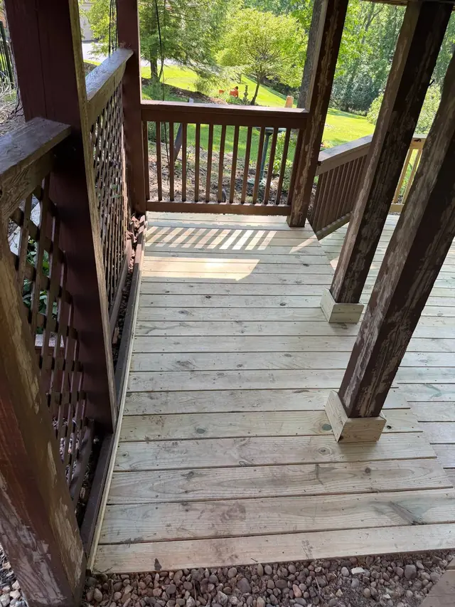 Fresh lower-deck boards fitted around existing brown posts with new wood base trim and visible cosmetic repairs