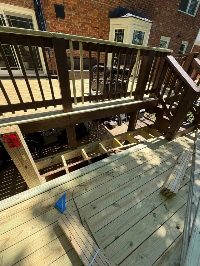 Partly installed middle-level decking, exposed framing and wood posts awaiting the new railings