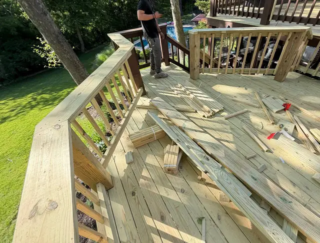Nearly completed middle-level wood railings with lumber offcuts and bundled balusters on the new deck boards