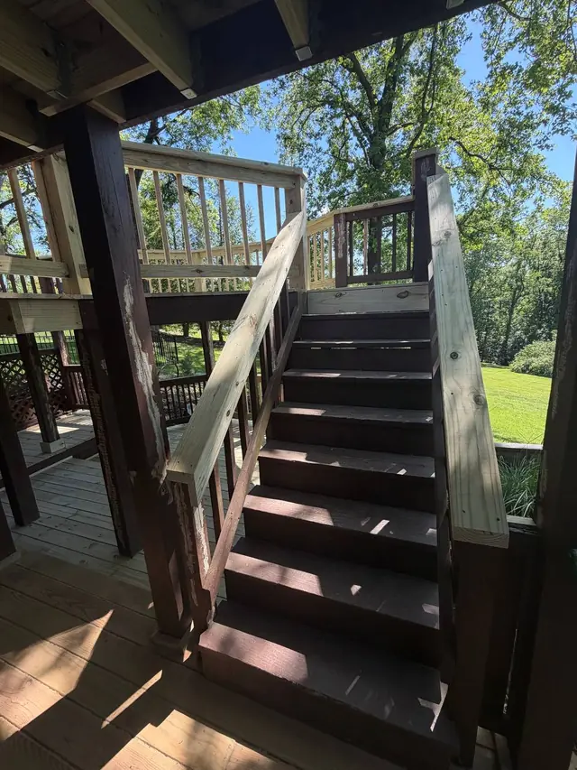 Existing brown deck stairs with newly replaced wood top rails leading to the restored middle level