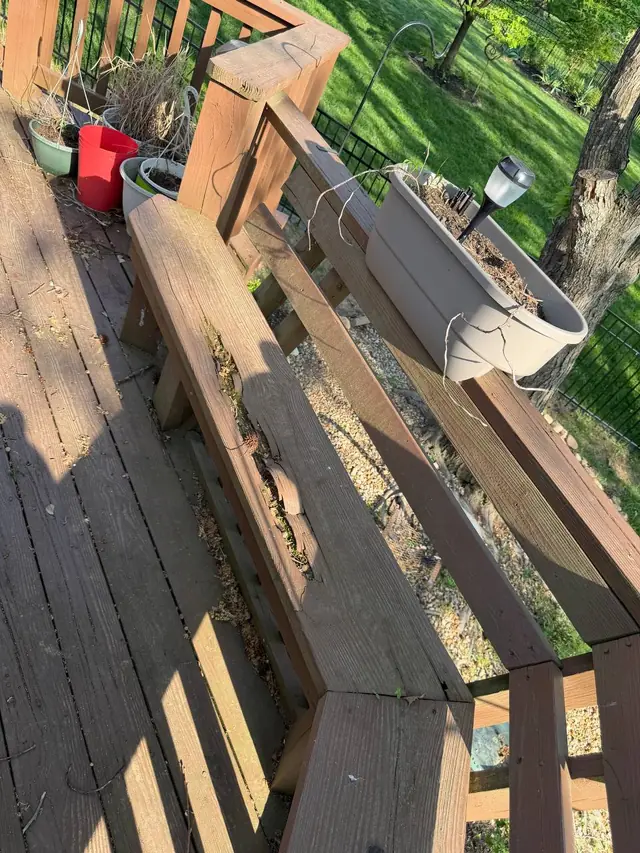 Split and rotted wood along the middle-level railing and bench, beneath a planter