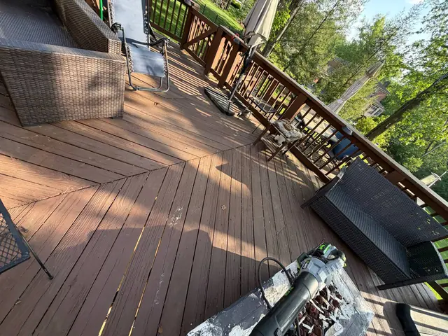 Old diagonal wood decking and brown railings on the furnished upper deck before restoration