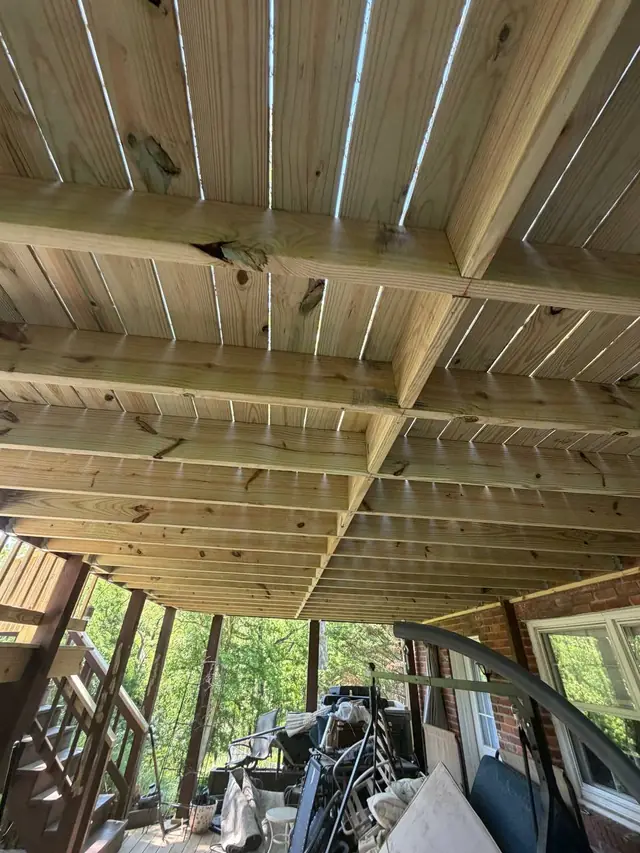 Long view beneath the upper deck showing new joists, rows of blocking and installed deck boards over existing supports