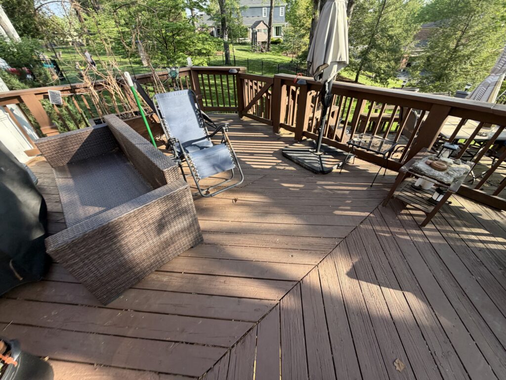 Before photo of an older deck with worn brown boards and diagonal board layout